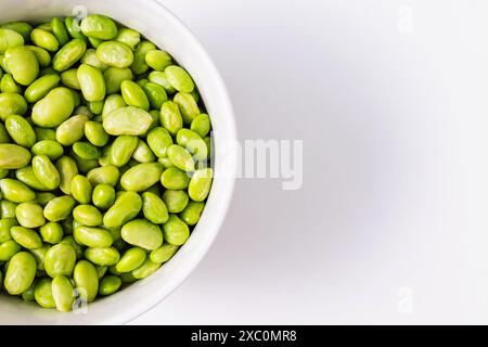 Soja vert cuit à la vapeur, edamame décortiqué dans un bol sur une table lumineuse Banque D'Images