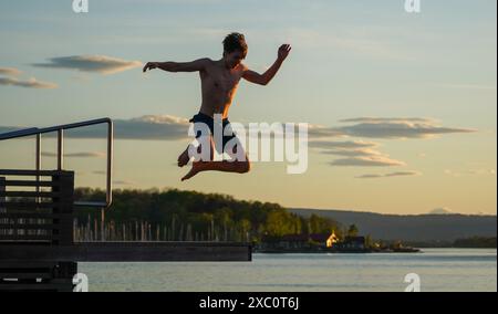 Un jeune homme saute à l'eau sur la promenade du port dans l'ancien quartier du port à conteneurs de Sørenga à Oslo, une partie complètement nouvelle de la ville. Banque D'Images