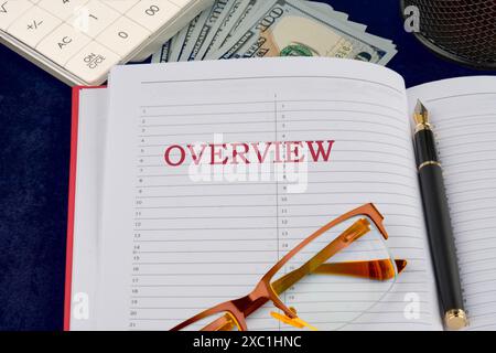 CONCEPT DE VUE D'ENSEMBLE. APERÇU écrit dans un cahier d'affaires dans une composition avec de l'argent, des lunettes, un stylo plume et des pièces d'une calculatrice Banque D'Images