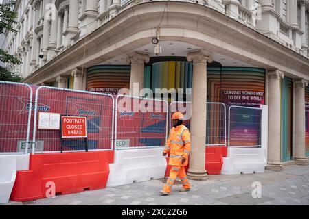 Un ouvrier de la construction passe devant l'extérieur de l'ancien grand magasin, Fenwick sur New Bond Street, le 13 juin 2024, à Londres, en Angleterre. 'Fenwick' a fermé en février 2024, sa propriété de Bond Street étant vendue à Lazari Investments pour plus de 400 millions de livres sterling. Banque D'Images