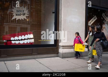 Les passants et les acheteurs interagissent avec un grand ensemble de dents bavardantes remontées, une version à grande échelle de l'original de 1949 d'Eddy Goldfarb appelé 'Yakity-Yak Talking Teeth' qui est présenté dans une vitrine du grand magasin Selfridges sur Oxford Street, le 13 juin 2024, à Londres, en Angleterre. Banque D'Images