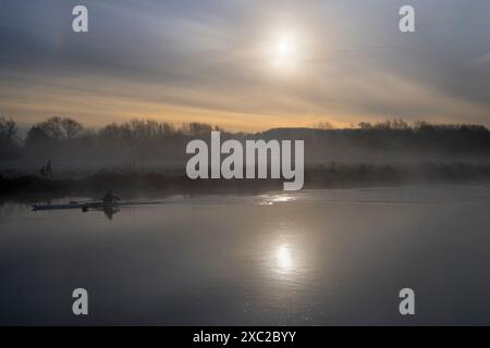 Ici, nous voyons la Tamise à Abingdon à son plus beau, avec un lever de soleil brumeux brillant lui donnant une beauté luminescente. Rameur de l'Oxford Univer Banque D'Images