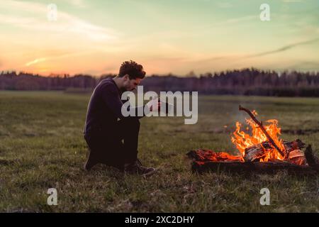 L'homme photographie un feu de camp, voyage de camping. Banque D'Images