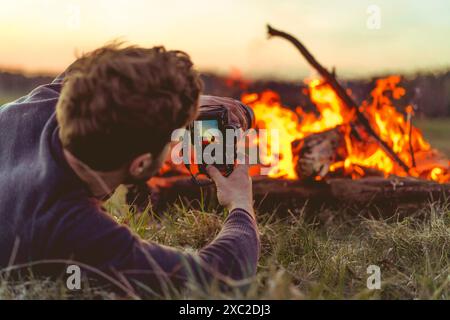 L'homme photographie un feu de camp, voyage de camping. Banque D'Images