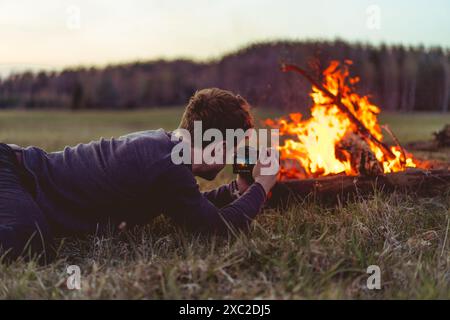 L'homme photographie un feu de camp, voyage de camping. Banque D'Images