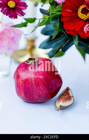Nature morte élégante avec grenade, figue et fleurs fraîches Banque D'Images