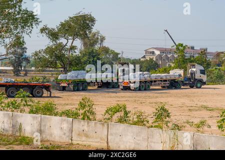 Camions avec de longues remorques chargées de sacs de marchandises en vrac garés en attente d'expédition à l'adresse de livraison. Banque D'Images