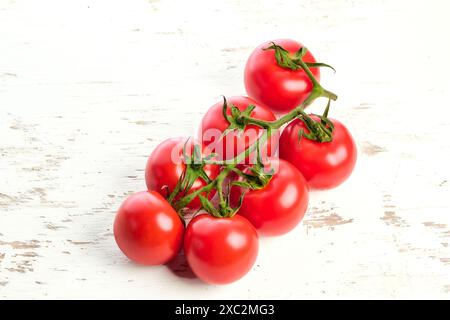 Brins de tomates cerises mûres sur une surface en bois blanc. Gros plan de tomates cerises. Banque D'Images