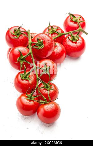 Deux brins de tomates cerises mûres sur une surface en bois blanc. Gros plan de tomates cerises. Orientation verticale de la photo. Banque D'Images