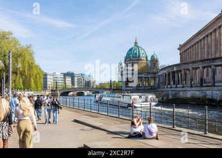 Berlin, Allemagne - 02 avril 2024, les gens sont assis sur le quai près de l'île aux musées, un bateau navigue le long du canal - printemps à Berlin. Banque D'Images