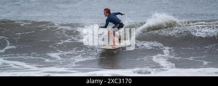 Gilgo Beach, New York, États-Unis - 30 août 2023 : un surfeur masculin chevauchant une vague lors d'une tempête de pluie au large des côtes de long Island. Banque D'Images