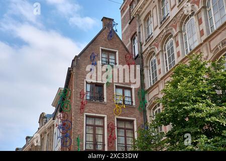 Vélos de nombreuses couleurs attachés à la maison près de la statue de Manneken Pis. Bâtiment haut de quatre étages décoré en brique rouge dans le centre de la ville de Banque D'Images