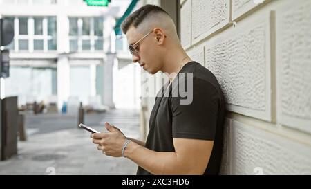 Bel homme hispanique à l'aide d'un smartphone sur la rue urbaine de la ville Banque D'Images