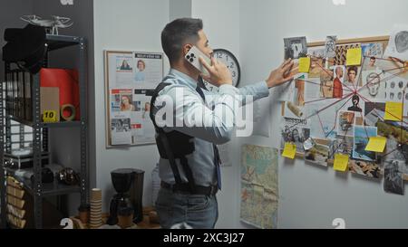 Un jeune homme hispanique avec une barbe examine des preuves à un poste de police tout en parlant au téléphone. Banque D'Images