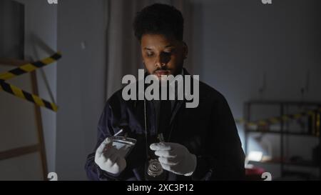 Beau détective afro-américain analysant des preuves sur la scène de crime à l'intérieur Banque D'Images