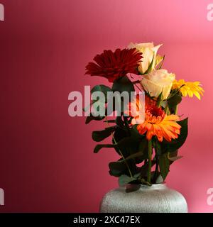 Bouquet de belles fleurs de gerbera et de roses dans un vase scintillant. Banque D'Images