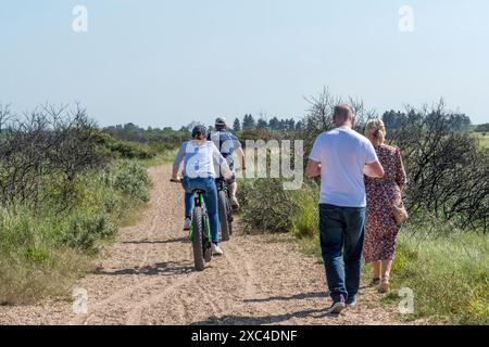 Les cyclistes sur les gros vélos passent devant les gens marchant le long du chemin derrière les plages de Snettisham et Heacham dans le Norfolk. Banque D'Images