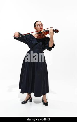 Élégance classique. Portrait de femme senior élégante en robe noire jouant avec âme du violon isolé sur fond blanc Banque D'Images