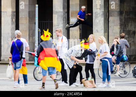 Berlin, Allemagne. 14 juin 2024. Football, UEFA Euro 2024, Allemagne - Écosse, tour préliminaire, Groupe A, jour de match 1 : un homme fait des exercices de fitness derrière des fans de football à un bâtiment d'entrée de la colonne de la victoire. Crédit : Christoph Soeder/dpa/Alamy Live News Banque D'Images