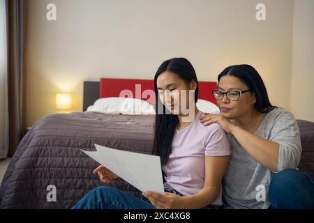 Famille de deux femmes regardant à travers la documentation dans la chambre Banque D'Images