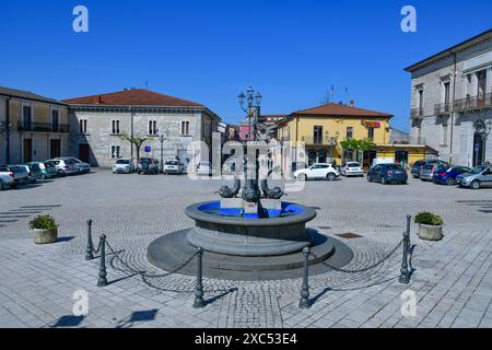 Une place de la ville avec une fontaine centrale et les bâtiments environnants sous un ciel bleu clair en Italie. Banque D'Images