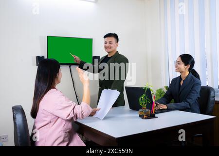 une équipe de bureau d'homme et de femme d'affaires devant un écran vert dans une table de réunion discutant Banque D'Images