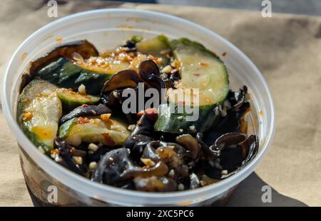 salade chinoise de champignons et de concombre (hors-d'œuvre épicé de restaurant accompagnant la nourriture dans un récipient en plastique à emporter) à emporter à emporter asie Banque D'Images