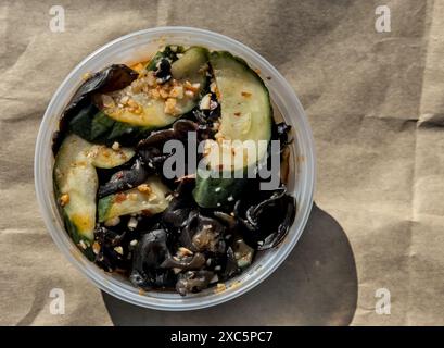 salade chinoise de champignons et de concombre (hors-d'œuvre épicé de restaurant accompagnant la nourriture dans un récipient en plastique à emporter) à emporter à emporter asie Banque D'Images