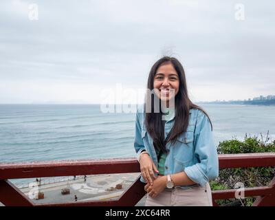 Lima, Pérou - juillet 30 2023 : femme péruvienne pose sur un balcon avec la mer derrière elle à Lima, Pérou Banque D'Images