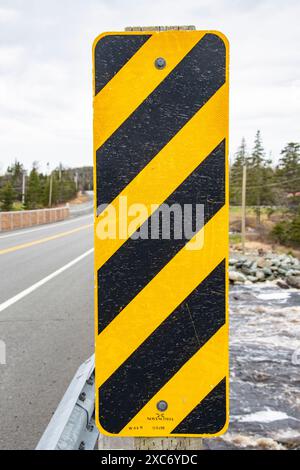 Panneau de danger rectangulaire jaune et noir à rayures diagonales sur un pont à Liscomb, Nouvelle-Écosse, Canada Banque D'Images