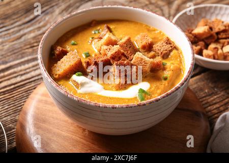 Bol de soupe à la crème savoureuse avec des croûtons sur fond de bois Banque D'Images