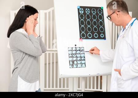 Médecin mûr montrant l'EEG au patient en clinique Banque D'Images