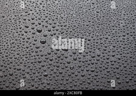 Vue de dessus de la goutte d'eau de pluie sur fond sombre. Banque D'Images