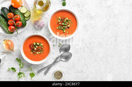 Soupe gazpacho de tomate d'été dans des bols sur fond de pierre claire avec espace de texte libre. Concept de nourriture saine. Vue de dessus, pose à plat Banque D'Images