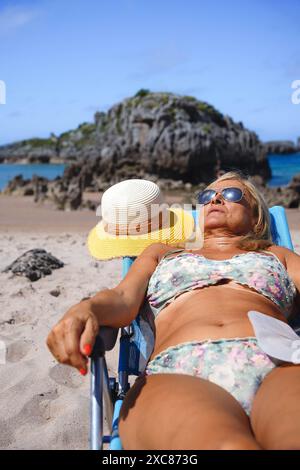 femme en bikini avec un sac de stomie bronzant sur la plage. Cancer du côlon Banque D'Images