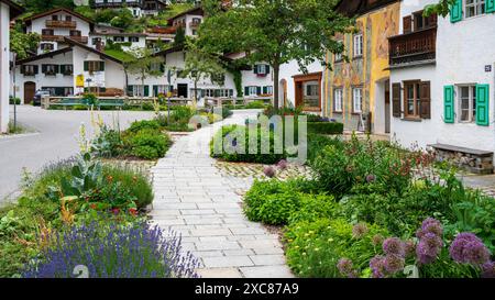 Die Marktgemeinde Mittenwald mit historischen Gebäuden Mittenwald liegt im Landkreis Garmisch-Partenkirchen, ist Deutschlands höchstgelegener Luftkurort und berühmt wegen der traditionellen Kunst des Geigenbaus. In der historischen Altstadt sind viele Häuser auf der Fassade mit kunstvoller Lüftlmalerei geschmückt. Direkt neben der historischen Altstadt liegt der Ortsteil Gries mit seinen historischen Gebäuden und den mit Blumen- und Pflanzenschmuck aufwendig gestalteten Freiflächen. Mittenwald Bayern Deutschland *** le bourg de Mittenwald avec ses bâtiments historiques est situé dans Mittenwald Banque D'Images