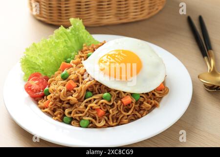 Gros plan Indomie Goreng, nouilles instantanées sautées avec œuf latéral ensoleillé sur le dessus. Nouilles instantanées populaires de Indonésie Banque D'Images