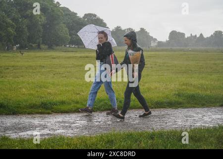 Londres, Royaume-Uni. 15 juin 2024. Les femmes bravent les fortes averses sur Wimbledon Common , au sud-ouest de Londres avec les prévisions pour le temps humide ce week-end . Credit : Amer Ghazzal/Alamy Live News Banque D'Images