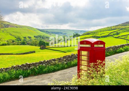 Cabine téléphonique rouge emblématique à l'ancienne à Keld, Swaledale, Yorkshire Dales, surplombant les prairies colorées de fleurs sauvages, les murs de pierres sèches et la pierre Banque D'Images