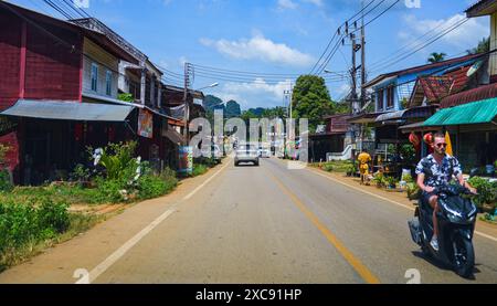 Route sinueuse passant par un village traditionnel entouré de falaises karstiques calcaires en Asie du Sud-est (Thaïlande, entre Krabi, Phang Nga et Phuk Banque D'Images