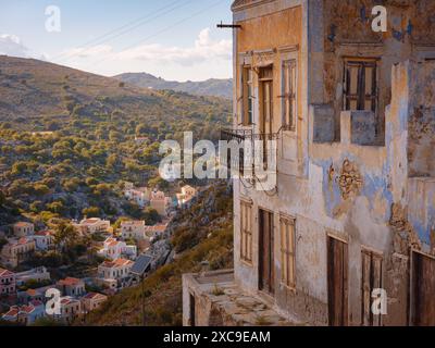 Île de Symi, Grèce. Vacances des îles grecques de Rhodos en mer Égée. Belles maisons néoclassiques colorées sur les collines d'une île grecque au coucher du soleil. Arrière-plan de voyage de vacances. Banque D'Images