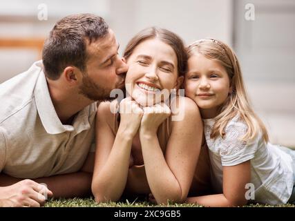 Heureux, famille et les gens avec baiser sur l'herbe pour le week-end plaisir, bonheur et confort dans l'enfance. Ludique, papa et maman avec fille à l'extérieur de la maison pour Banque D'Images