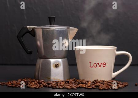 Tasse à café avec amour écrit dessus. Cafetière avec grains torréfiés. Banque D'Images
