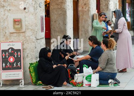 QATAR SHOPPING Eid Al-Adha PRÉPARATION 2024 les femmes appliquent un design traditionnel au henné sur leurs mains au marché traditionnel du Souq Waqif avant le prochain Aid al-Adha à Doha, Qatar, le 15 juin 2024. Les musulmans du Qatar célébreront l’Aïd al-Adha le 16 juin 2024, la Fête du sacrifice, qui marque la fin du pèlerinage du Hadj à la Mecque et commémore la volonté du prophète IbrahamÕs de sacrifier son fils pour montrer son obéissance à Dieu. DOHA Qatar Copyright : xNOUSHADx Banque D'Images