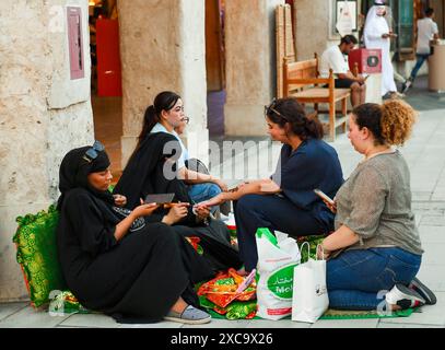 QATAR SHOPPING Eid Al-Adha PRÉPARATION 2024 les femmes appliquent un design traditionnel au henné sur leurs mains au marché traditionnel du Souq Waqif avant le prochain Aid al-Adha à Doha, Qatar, le 15 juin 2024. Les musulmans du Qatar célébreront l’Aïd al-Adha le 16 juin 2024, la Fête du sacrifice, qui marque la fin du pèlerinage du Hadj à la Mecque et commémore la volonté du prophète IbrahamÕs de sacrifier son fils pour montrer son obéissance à Dieu. DOHA Qatar Copyright : xNOUSHADx Banque D'Images