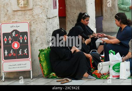 QATAR SHOPPING Eid Al-Adha PRÉPARATION 2024 les femmes appliquent un design traditionnel au henné sur leurs mains au marché traditionnel du Souq Waqif avant le prochain Aid al-Adha à Doha, Qatar, le 15 juin 2024. Les musulmans du Qatar célébreront l’Aïd al-Adha le 16 juin 2024, la Fête du sacrifice, qui marque la fin du pèlerinage du Hadj à la Mecque et commémore la volonté du prophète IbrahamÕs de sacrifier son fils pour montrer son obéissance à Dieu. DOHA Qatar Copyright : xNOUSHADx Banque D'Images