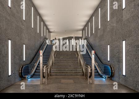 Une grande station de métro vide, moderne, grise et blanche avec deux escaliers mécaniques. Les escaliers roulants se trouvent à gauche et à droite de la gare Banque D'Images