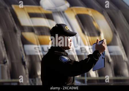 Le U.S. Customs and Border Protection officer Alan Syto les gestes pour une file de camions en attente d'inspection non intrusive des rayons x à l'extérieur de Levi's Stadium d'aller de l'avant comme opérations de sécurité sont menées avant le Super Bowl 50 à Santa Clara, Californie, le 1 février 2016. (U.S. Customs and Border Protection Photo par Glenn Fawcett) Banque D'Images