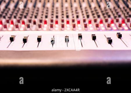 Panneau de commande bureau avec curseurs et faders motorisés dans un studio d'enregistrement professionnel, console de mixage utilisée dans l'édition d'enregistrements. Commutateurs, boutons et boutons utilisés en production. Gros plan. Banque D'Images