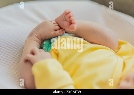 La peau du nouveau-né pèle. Maman utilise des produits pour la peau et des massages pour soigner et apaiser la peau délicate du bébé, assurant confort et promotion Banque D'Images